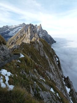 Blick über den felsigen Bergrücken zum Säntisgipfel und über das wolkenverhangene Tal
