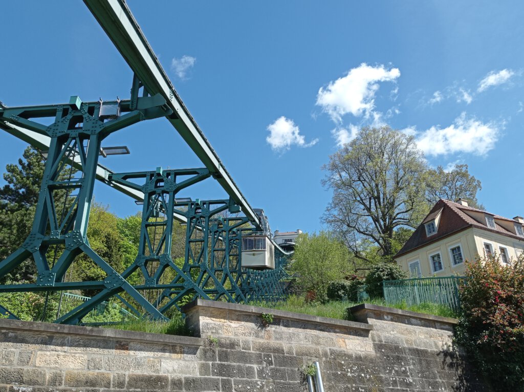 Dresdner Schwebebahn an blauen Stahlträgern über Weinberg und Villen