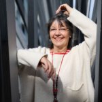 Ulrike Wanner, Mediatorin bei Alles Porträtfoto von Ulrike Wanner, Mediatorin und Inhaberin von Alles gut Mediation, aufgenommen im Freien zwischen schmalen Metallstreben. Verwendet als Beitragsbild für den Artikel 'Klarheit statt Win-Win': 5 Dinge, die ich als Mediatorin heute anders machen würde'