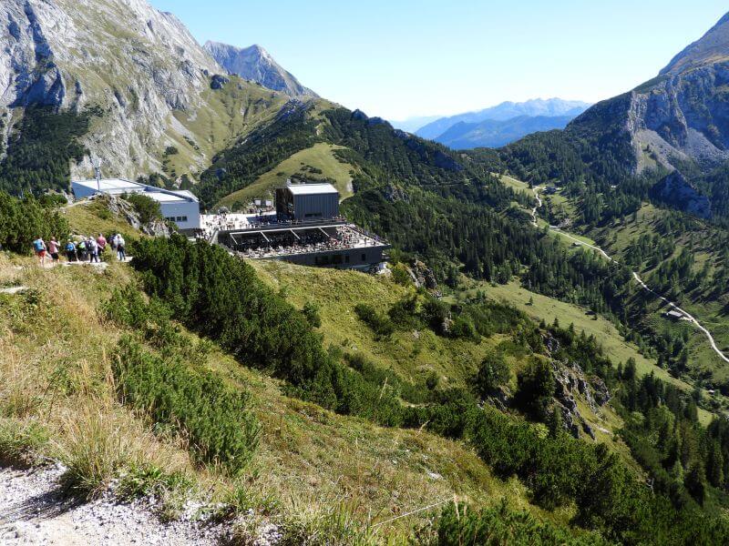 Bergstation mit Terrasse und vielen Menschen vor Bergpanorama