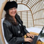 Ulrike Wanner mit Laptop im Rattan-Sessel, Autorin der Umfrage zum Thema Konflikt mit KI lösen.